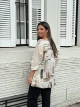 Blusa beige de lino con estampado abstracto en tonos marrones y grises, de corte holgado, manga 3/4 y bolsillos delanteros.