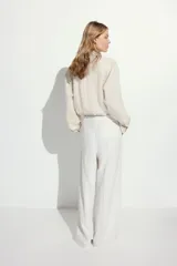 Camisa color crema de mezcla de lino y viscosa con cuello, botones adelante y canesú de doble capa con pliegue de caja en la espalda. Modelo de manga larga con bolsillo superior abierto, puños abotonados y bajo redondeado.