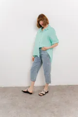 Camisa color verde agua, confeccionada en lino, de corte amplio, con cuello camisero, botones en el frente y mangas 3/4 que se pueden arremangar.