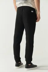 Pantalón de jogging negro de felpa con puños y cintura ajustable con cordón. Presenta logo de goma en la pierna izquierda y bolsillos laterales.