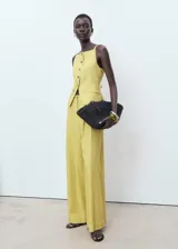 Pantalón de tiro alto, diseño recto y largo, color amarillo claro con finas rayas verticales. Presenta cierre de botón y cremallera, detalle de pinzas y dos bolsillos laterales.