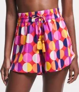 Short de playa con cintura elástica y lazo decorativo. Estampado de lunares grandes en tonos rosa, naranja, amarillo, blanco y violeta.