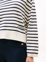 Buzo de punto con cuello en v y diseño de rayas horizontales azules y blancas.