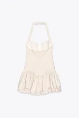 Minivestido blanco con cuello halter, escote recto y falda con volantes y forro tipo short. Presenta cierre con botones en el cuello y cremallera oculta en la espalda.