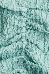 Top color celeste con textura arrugada, escote en V, mangas cortas y frunces en el delantero y los laterales.