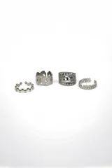 Set de cuatro anillos plateados con diferentes diseños: uno con bolitas, uno con mariposas caladas, uno con strass y uno con flores caladas.