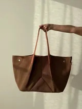 Bolso negro tipo tote de neopreno con bolsillo interno de red, sobre haciendo juego y gancho para sujetarlo.