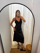 Vestido largo negro de seda, con escote en V adornado con encaje delicado y tirantes finos.