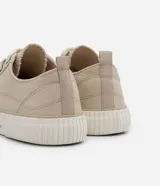 Championes bajos de lona color beige, con puntera redonda, cierre con cordones y suela de goma blanca con detalle de línea en relieve.