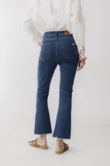 Pantalón jean cropped azul con corte acampanado y ruedo desflecado.