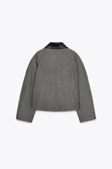 Chaqueta corta de tweed gris con cuello solapa y puños de cuero negro. Cierre frontal con botones ocultos.