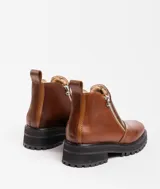 Bota de cuero vacuno color marrón, con interior forrado en corderito natural. Tiene suela de goma artesanal, punta cuadrada, cierre YKK en ambos lados y caña de 11cm.
