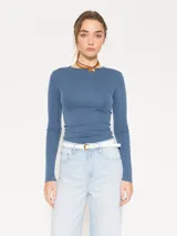 Remera azul de punto, con textura suave al tacto, mangas largas, escote redondo y espalda amplia y abierta.