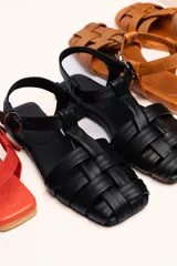 Sandalias franciscanas rojas de cuero con tiras entretejidas y hebilla lateral.