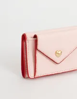 Billetera pequeña de cuerina color rosa claro con solapa en forma de sobre y broche de corazón dorado.
