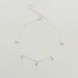 Tobillera de plata 925 con cadena fina y cinco dijes colgantes: dos con forma de lágrima y tres con forma cuadrada, todos engastados con circones brillantes.