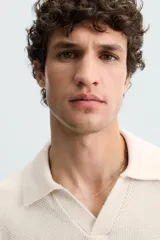 Polo color crema de punto con cuello solapa y abertura frontal en V.