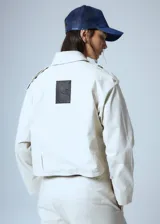 Campera corta color beige confeccionada en gabardina con lazo para ajustar en cintura, botones de pasta en charreteras y chapa RENÉE cursiva cosida a mano en el delantero.