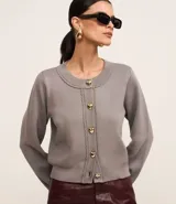 Cardigan de punto texturizado color gris con cuello redondo, abotonado delantero con botones de corazón y mangas largas con puños ajustados.