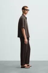 Pantalón de corte relajado (relaxed fit) color verde militar, confeccionado en mezcla de algodón y lino. Presenta cintura elástica ajustable con cordón y bolsillos frontales y traseros de vivo.