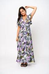 Vestido largo con estampado floral en tonos lila, verde y blanco, con escote en V, mangas cortas con volados y lazo ajustable en la cintura.