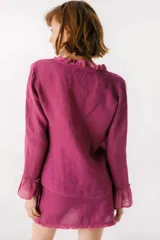 Blusa blanca de lino con botones de nácar, volados en el escote y mangas largas con puños acampanados. Corte recto y holgado.