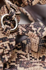 Sandalias bajas color marrón con estampado de piel de serpiente, tira delantera con detalle de hebillas y tira trasera con hebilla metálica.