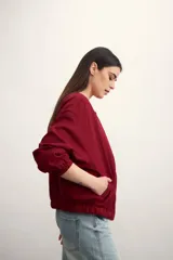 Chaqueta bomber negra con cierre frontal dorado y mangas largas con puños elásticos.