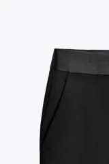 Pantalón negro de tiro alto con corte flare y cinturilla combinada a tono. Presenta bolsillos laterales y falsos bolsillos de vivo en la espalda.