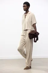 Pantalón de tiro alto color beige, con cintura elástica ajustable con cordones, bolsillos delanteros y pernera ancha.