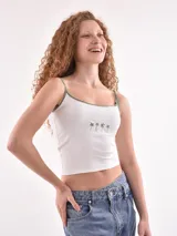 Musculosa blanca con tirantes finos en verde y estampado de palmeras en el pecho.