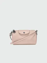 Bandolera Longchamp modelo Le Pliage Xtra XS, color rosa pálido, con correa ajustable y cierre de solapa con botón a presión.