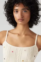 Musculosa de punto color crema con breteles finos y bordado de pequeñas estrellas de colores.