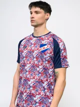 Remera de fútbol Umbro del Club Nacional de Football, modelo Pro Training Active. Diseño con estampado abstracto en blanco, rojo y azul, con mangas raglán azul marino y escudo del club en el pecho.