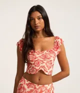 Blusa corta de tule con estampado de caracolas y peces en tonos rojo y blanco. Tiene escote cuadrado, mangas cortas con volados y fruncido en el busto.