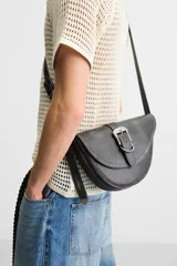 Bandolera negra de cuero sintético con hebilla metálica al frente y correa ajustable.