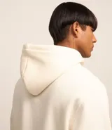 Buzo comfort para hombre hecho con algodón más sostenible. La prenda tiene capucha, cordón para ajuste, bolsillos, mangas largas y estampa "live without warning".