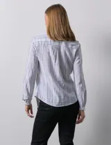Blusa de lino a rayas verticales blancas y grises, marca Zac & Rachel. Tiene cuello a la base, escote en V y abertura central con botones. Cuenta con dos bolsillos en el pecho y mangas largas regulables con presilla y botón.
