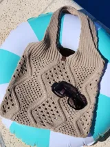 Bolso tejido de hilo color beige, con diseño calado y asas anchas.