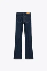 Pantalón de jean azul oscuro, de tiro medio, corte bootcut y largo hasta el tobillo. Tiene cinco bolsillos, trabillas en la cintura y cierre frontal con cremallera y botón metálico.