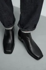 Bota de piel negra con cierre de cremallera lateral, horma cuadrada y tacón de 5 cm.