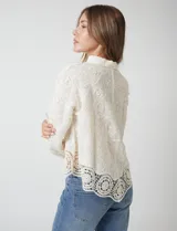 Camisa de algodón color naranja, con bordado suizo y encaje calado. Tiene cuello con solapa, botones frontales, mangas largas con terminación de encaje y ruedo asimétrico con galón de encaje.