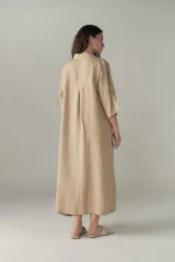 Vestido largo color beige de lino, con cuello camisero, media cartera con un botón, mangas 3/4 con tajos y bolsillos laterales.