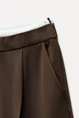 Pantalón ancho gris con textura de espiga, tiro alto, doble cintura elástica ajustable con cordón, pinzas frontales, bolsillos delanteros y falso bolsillo de vivo en la espalda.