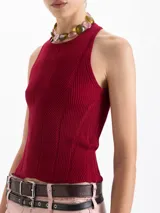 Top de punto acanalado color negro, ajustado al cuerpo y de largo por encima de la cadera. Presenta cuello redondo cerrado y breteles cruzados en la espalda. Confeccionado en hilado frío.