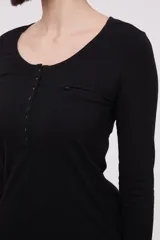 Remera de manga larga entallada en color blanco, confeccionada en algodón. Presenta cuello redondo con una hilera de botones frontales y un pequeño bolsillo en el pecho con detalle de botón.