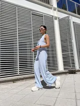 Pantalón celeste a rayas verticales blancas, de corte palazzo y cintura alta con elástico.