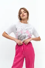 Remera gris de algodón con estampado de flor en tonos rosa y blanco. Tiene cuello redondo, mangas cortas y corte recto.