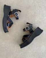 Sandalias negras de cuero vacuno con textura reptil, plataforma y hebilla plateada.