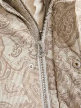 Campera puffer de corderoy con estampado paisley en tonos beige y cuello alto.